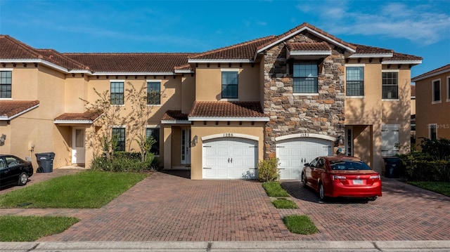 townhome / multi-family property with a tile roof, a garage, driveway, and stucco siding