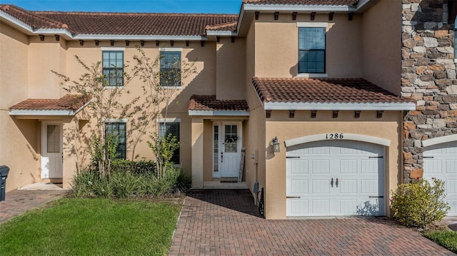 view of front facade with a tiled roof, decorative driveway, and stucco siding