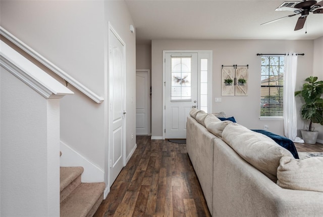 living room featuring baseboards, ceiling fan, stairway, and dark wood-style flooring
