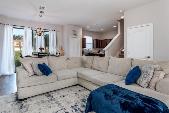 living area featuring stairs, recessed lighting, visible vents, a notable chandelier, and wood finished floors