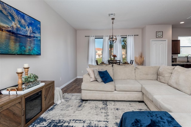 living area featuring baseboards, visible vents, an inviting chandelier, and wood finished floors