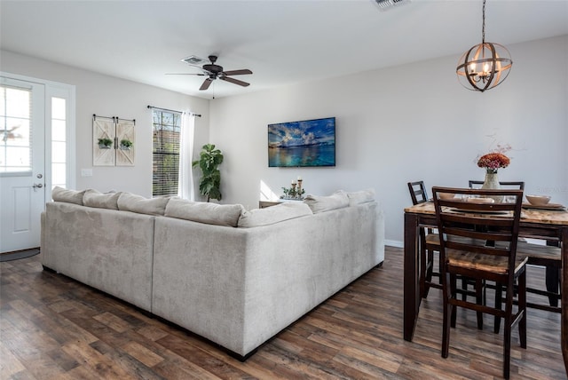 living room featuring visible vents, ceiling fan with notable chandelier, and dark wood finished floors