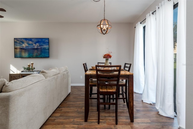 dining area featuring ceiling fan with notable chandelier, dark wood-style floors, and baseboards