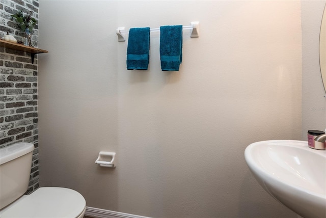bathroom featuring baseboards, toilet, and a sink