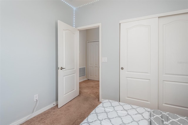 bedroom with baseboards, a closet, light colored carpet, and visible vents