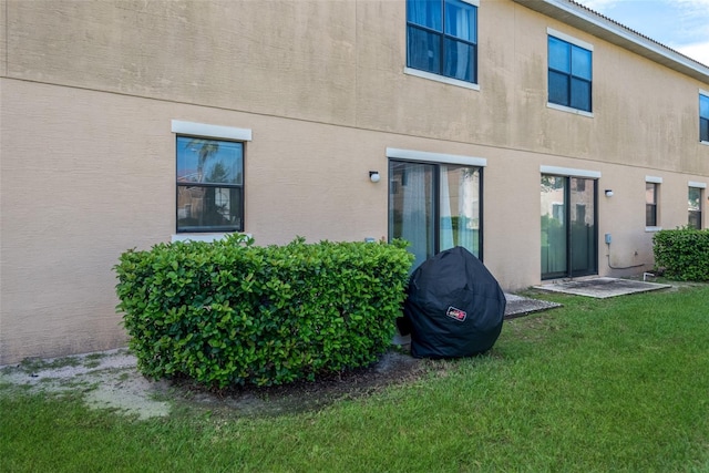 back of property with a lawn and stucco siding