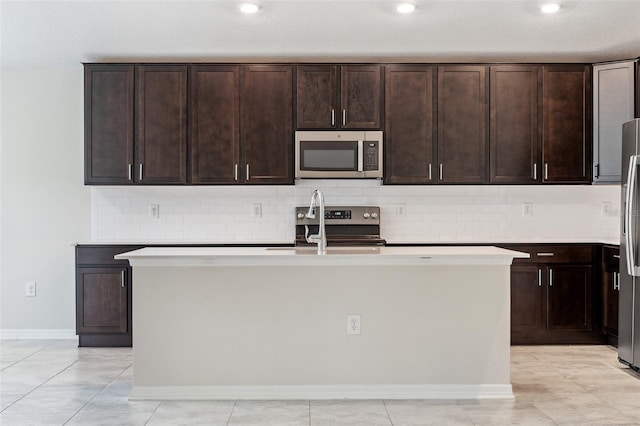 1848 Ancestry Trl, Kissimmee, FL 34746 - kitchen with appliances with stainless steel finishes, tasteful backsplash, a center island with sink, and dark brown cabinetry