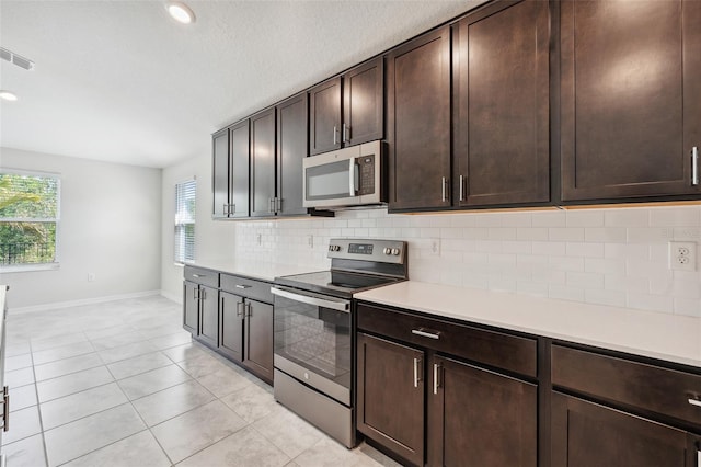 1848 Ancestry Trl, Kissimmee, FL 34746 - kitchen featuring appliances with stainless steel finishes, light countertops, decorative backsplash, dark brown cabinetry, and light tile patterned floors