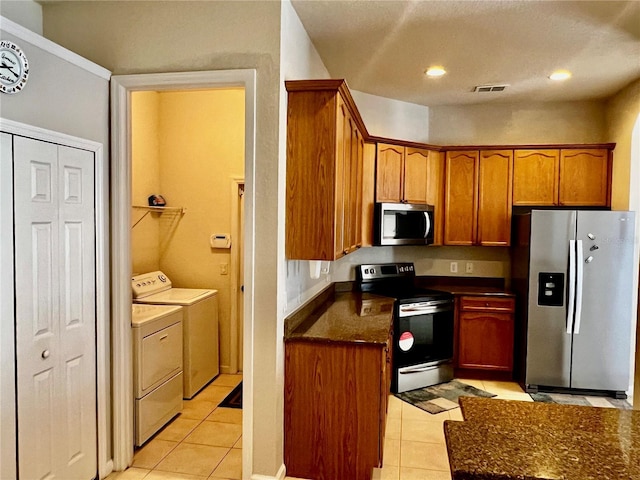 2920 River Birch Dr, Kissimmee, FL 34741 - kitchen with washer and clothes dryer, light tile patterned floors, stainless steel appliances, dark countertops, and brown cabinets