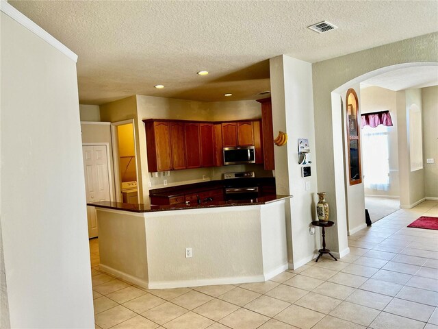 2920 River Birch Dr, Kissimmee, FL 34741 - kitchen with dark countertops, arched walkways, appliances with stainless steel finishes, and light tile patterned floors