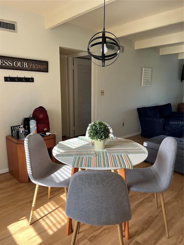 dining space with visible vents, a chandelier, wood finished floors, baseboards, and beam ceiling