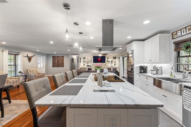 1999 Sir Lancelot Cir, Saint Cloud, FL 34772 - kitchen featuring a sink, open floor plan, white cabinetry, island range hood, and a kitchen island