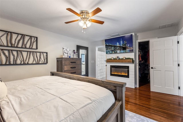 1999 Sir Lancelot Cir, Saint Cloud, FL 34772 - bedroom with visible vents, a glass covered fireplace, a spacious closet, wood finished floors, and a closet