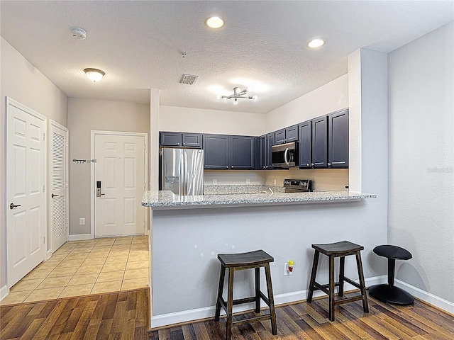 kitchen featuring a breakfast bar, wood finished floors, visible vents, and appliances with stainless steel finishes