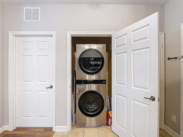 washroom featuring baseboards, visible vents, stacked washer / dryer, and laundry area