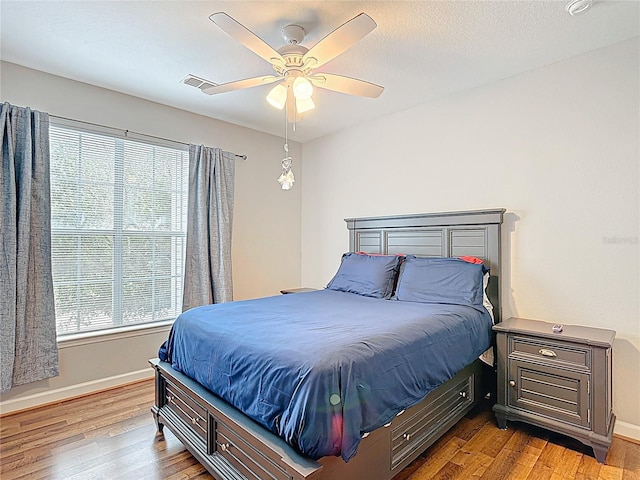 bedroom featuring baseboards, wood finished floors, and visible vents