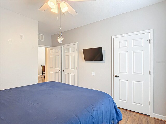 bedroom featuring wood finished floors, visible vents, baseboards, and ceiling fan