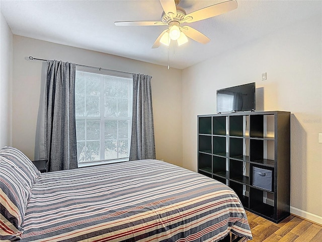 bedroom with ceiling fan, baseboards, and wood finished floors