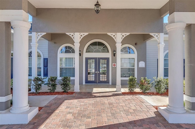 property entrance featuring a porch, french doors, and stucco siding