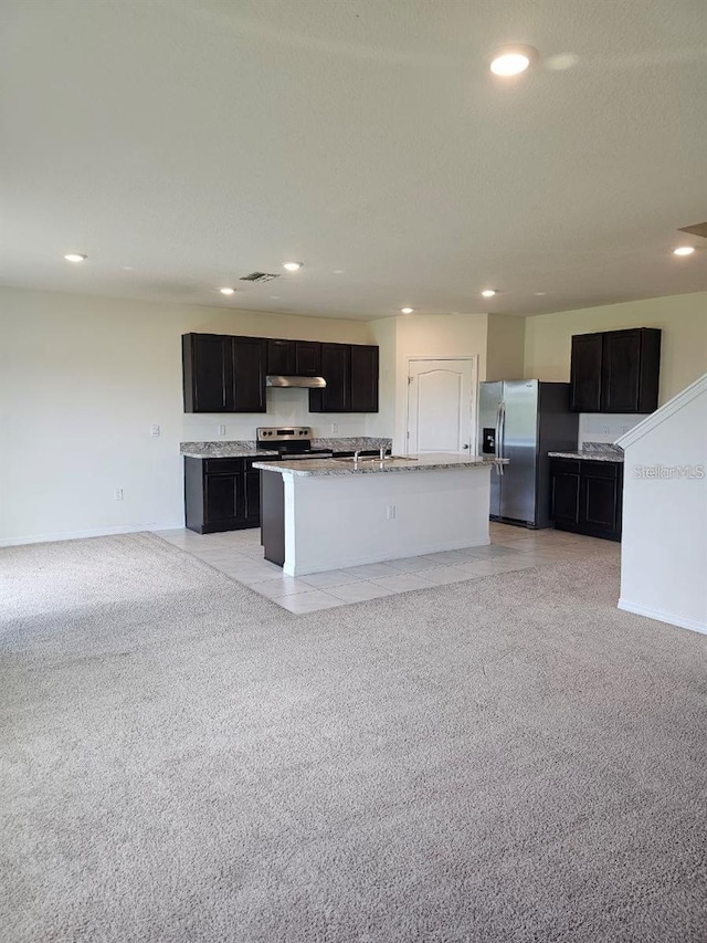 kitchen featuring appliances with stainless steel finishes, an island with sink, dark cabinetry, under cabinet range hood, and recessed lighting
