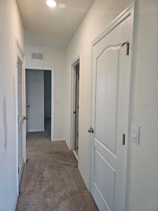 hallway featuring baseboards, visible vents, and carpet floors