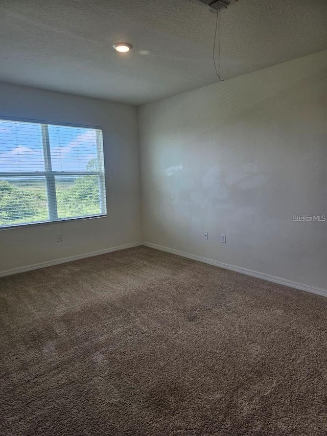 carpeted spare room featuring baseboards and a textured ceiling