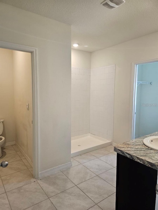 full bath with a stall shower, tile patterned flooring, a textured ceiling, toilet, and visible vents