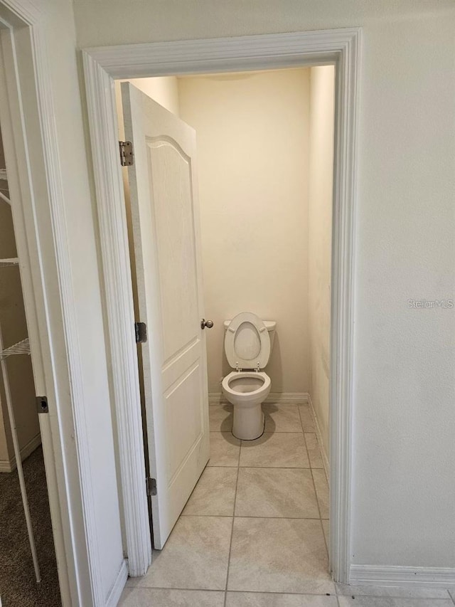 bathroom with toilet, tile patterned flooring, and baseboards