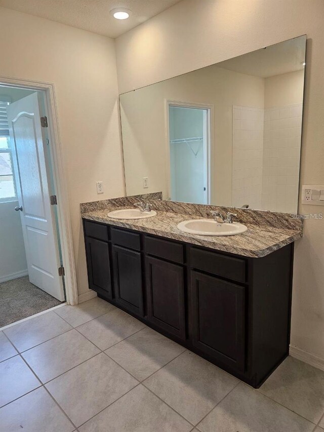 full bathroom featuring a sink, tile patterned floors, double vanity, and baseboards