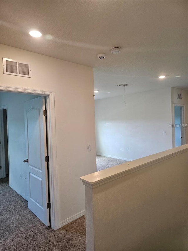 hall featuring recessed lighting, carpet, visible vents, and baseboards