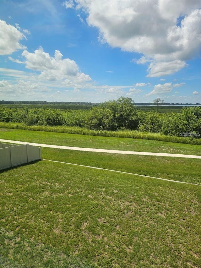 view of home's community with a yard, fence, and a rural view