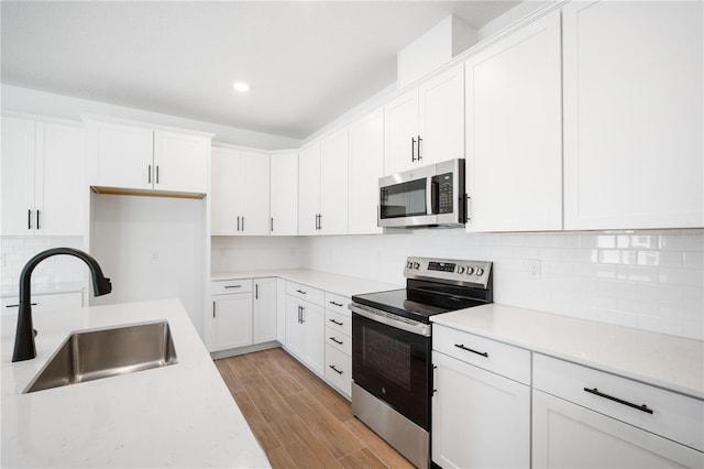 9143 Players Dr, Weeki Wachee, FL 34613 - kitchen with stainless steel appliances, backsplash, white cabinetry, light countertops, and recessed lighting