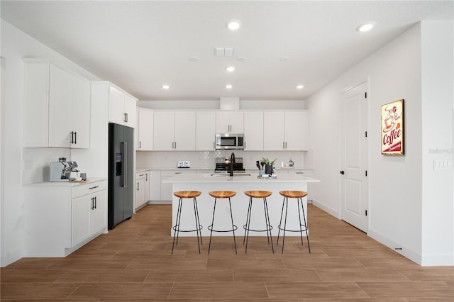 9143 Players Dr, Weeki Wachee, FL 34613 - kitchen with appliances with stainless steel finishes, a kitchen bar, light wood-style floors, light countertops, and white cabinetry