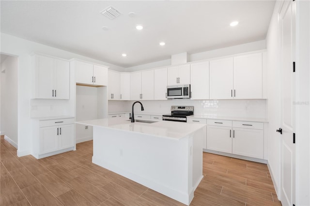 9143 Players Dr, Weeki Wachee, FL 34613 - kitchen featuring appliances with stainless steel finishes, decorative backsplash, light countertops, a center island with sink, and recessed lighting