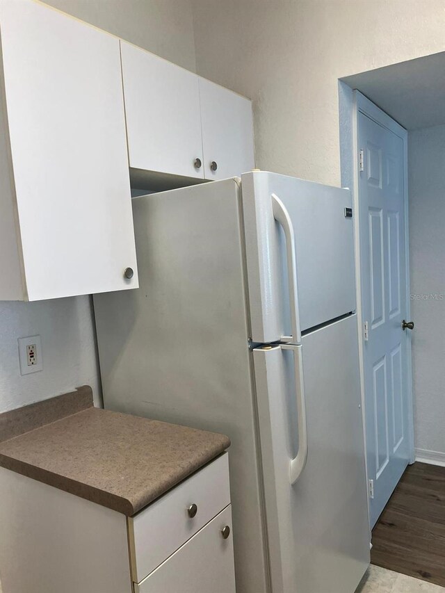 2314 Midtown Ter Unit 1113, Orlando, FL 32839 - kitchen featuring white cabinetry, wood finished floors, dark countertops, and freestanding refrigerator