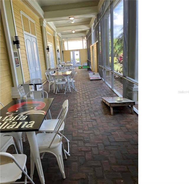 2314 Midtown Ter Unit 1113, Orlando, FL 32839 - sunroom featuring wood walls, beamed ceiling, ceiling fan, outdoor dining area, and brick floor