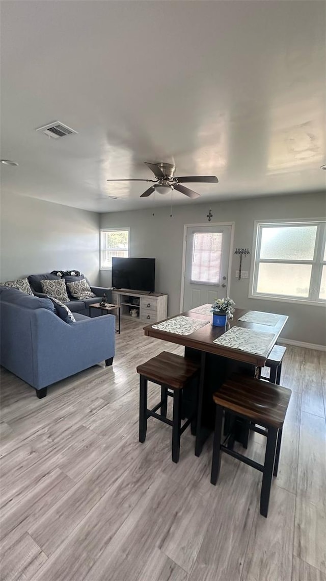 dining room featuring baseboards, visible vents, a ceiling fan, and light wood finished floors