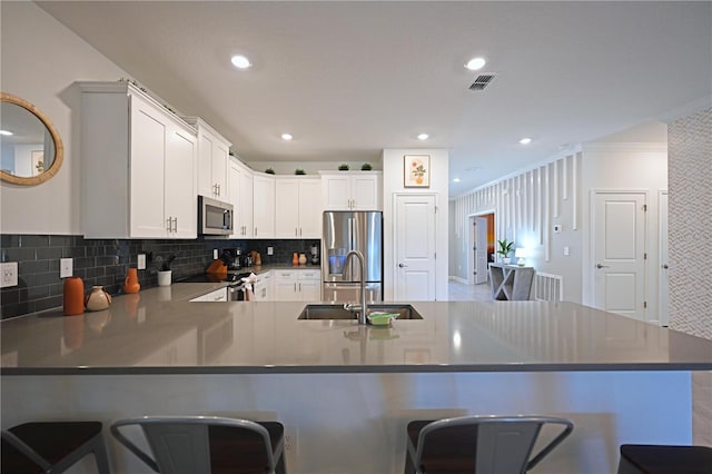 4221 Paragraph Dr, Kissimmee, FL 34746 - kitchen featuring a kitchen bar, a sink, visible vents, a peninsula, and appliances with stainless steel finishes