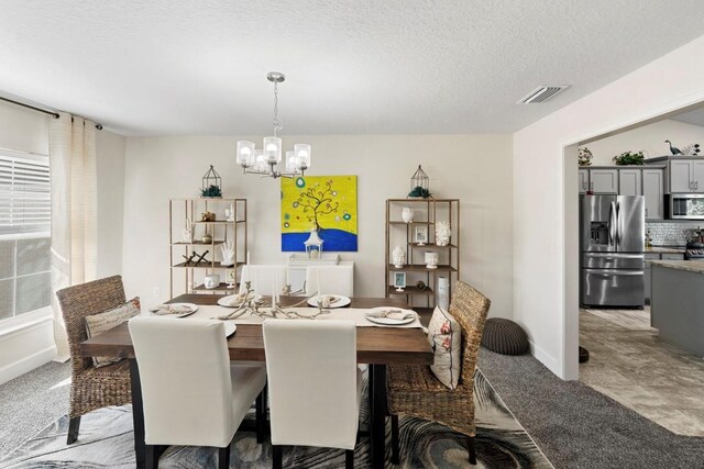 311 Athabasca Pl, Kissimmee, FL 34759 - dining room with a textured ceiling, visible vents, a chandelier, baseboards, and light colored carpet
