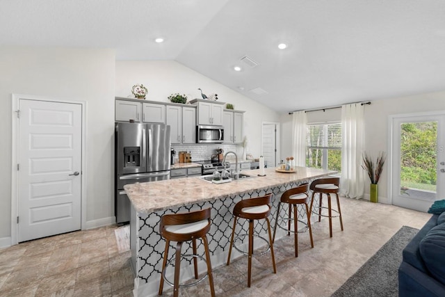 311 Athabasca Pl, Kissimmee, FL 34759 - kitchen featuring a kitchen breakfast bar, lofted ceiling, a sink, an island with sink, and appliances with stainless steel finishes
