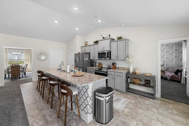 311 Athabasca Pl, Kissimmee, FL 34759 - kitchen with gray cabinets, a kitchen bar, appliances with stainless steel finishes, a center island with sink, and lofted ceiling