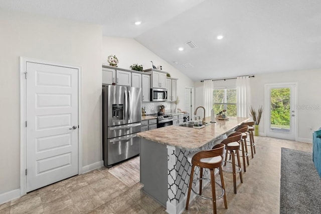 311 Athabasca Pl, Kissimmee, FL 34759 - kitchen with an island with sink, gray cabinets, a sink, a breakfast bar area, and stainless steel appliances