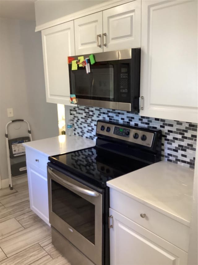 2948 Willow Bend Blvd, Orlando, FL 32808 - kitchen featuring light countertops, white cabinetry, appliances with stainless steel finishes, wood finish floors, and decorative backsplash