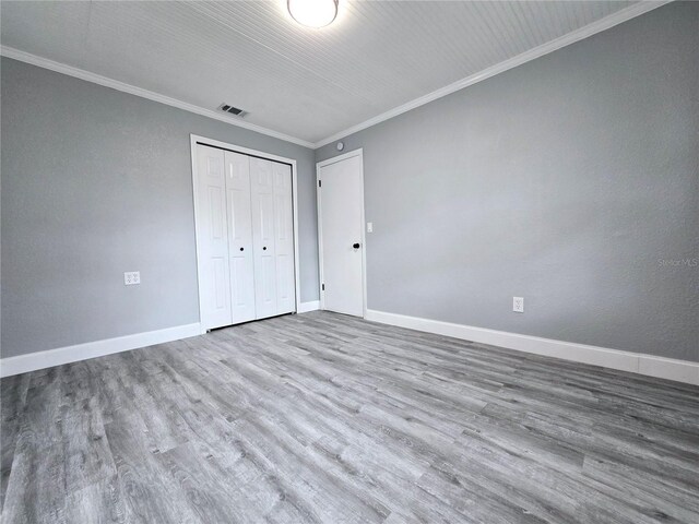 218 W Magnolia Ave, Longwood, FL 32750 - unfurnished bedroom with crown molding, wood finished floors, a closet, baseboards, and visible vents