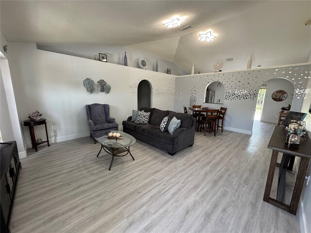 282 SE Walsh Ter, Port St Lucie, FL 34983 - living area with arched walkways, light wood finished floors, a textured ceiling, lofted ceiling, and baseboards