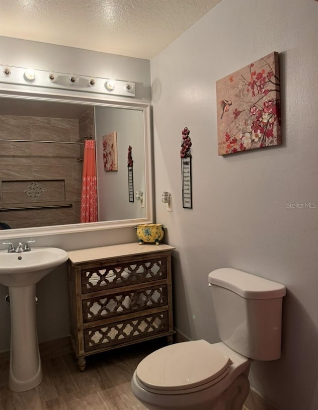 282 SE Walsh Ter, Port St Lucie, FL 34983 - full bathroom featuring toilet, wood finished floors, a shower with curtain, a textured ceiling, and baseboards
