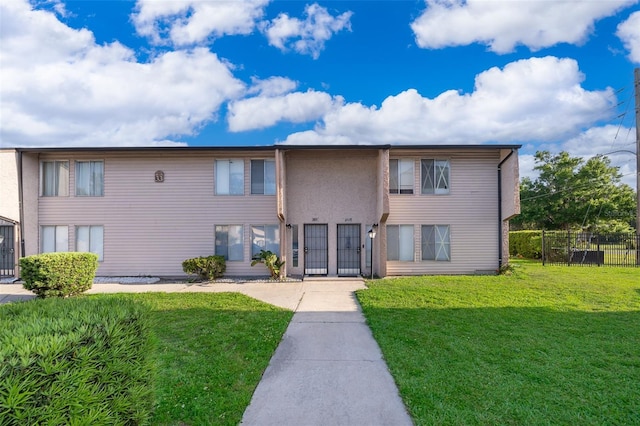 view of front of house with a front lawn, fence, and stucco siding