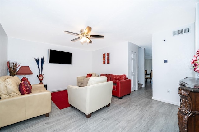 living room with visible vents, baseboards, light wood-type flooring, and a ceiling fan