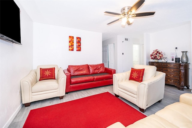 living area with visible vents, baseboards, wood finished floors, and ceiling fan