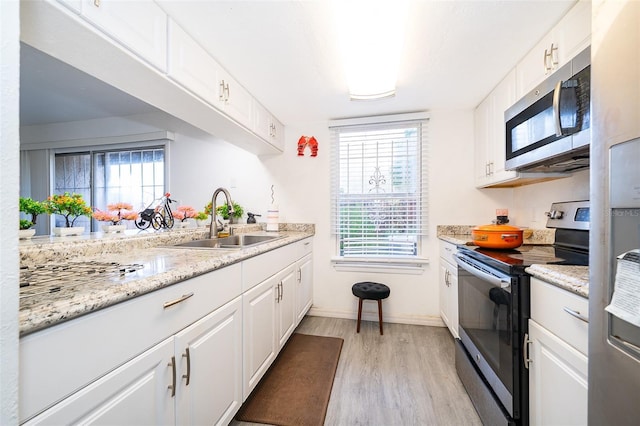 kitchen featuring light wood-type flooring, plenty of natural light, white cabinets, appliances with stainless steel finishes, and a sink